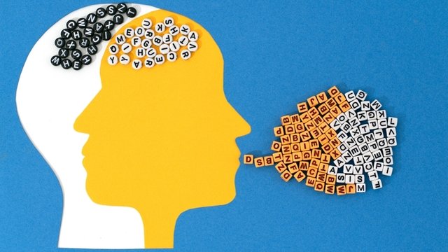 dos cabezas recortadas en papel que se cruzan, una blanca y otra amarilla, con patrones de letras en el área del cerebro