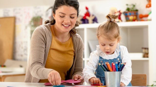 maestra de preescolar ayuda a una niña con un rompecabezas