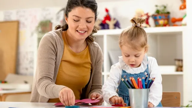 maestra de preescolar ayuda a una niña con un rompecabezas