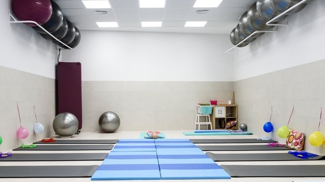 aula de psicomotricidad con colchonetas coloridas, juguetes, pelotas de fitness y globos