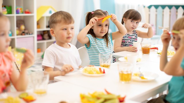 niños comiendo verduras en el comedor de la guardería