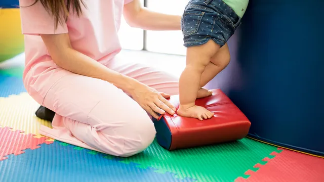 persona adulta haciendo ejercicios en una sala de psicomotricidad con un niño pequeño
