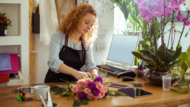chica joven hace un ramo de flores en una florister&iacute;a