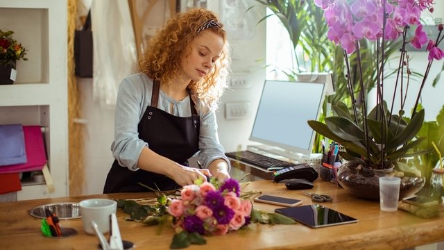 chica joven hace un ramo de flores en una floristería