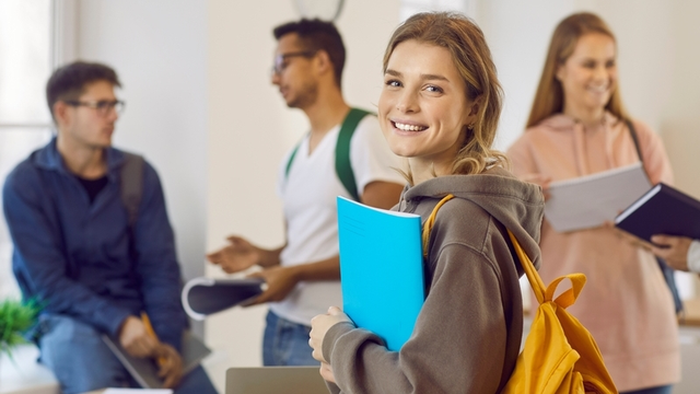 estudiante de FP mirando a cámara con mochila puesta en la espalda y sosteniendo un cuaderno
