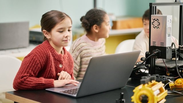 Retrato de diversas niñas jóvenes que se involucran en actividades STEM con computadoras portátiles y equipos robóticos en el entorno del aula, creando un entorno colaborativo para el aprendizaje y la innovación