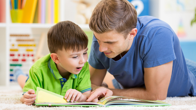 ni&ntilde;o y adulto leyendo un libro en el suelo