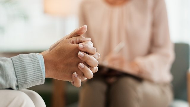 manos nerviosas de una mujer hablando con un/a psicólogo/a en una consulta o gabinete