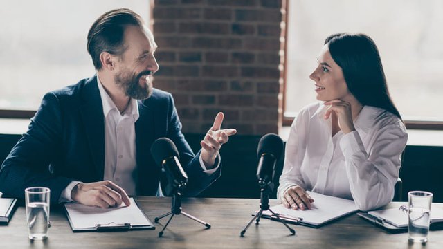 dos personas mantienen una conversación delante de unos micrófonos