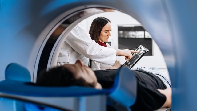 un paciente se somete a una resonancia magnética o TAC con profesionales a su lado