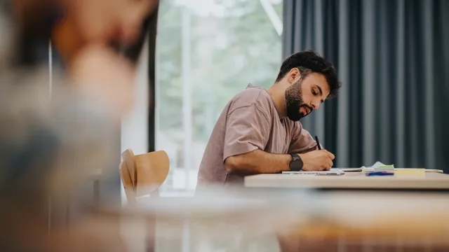 estudiante está concentrado escribiendo en un aula