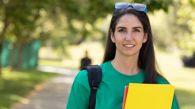 chica estudiante al aire libre sosteniendo unas carpetas