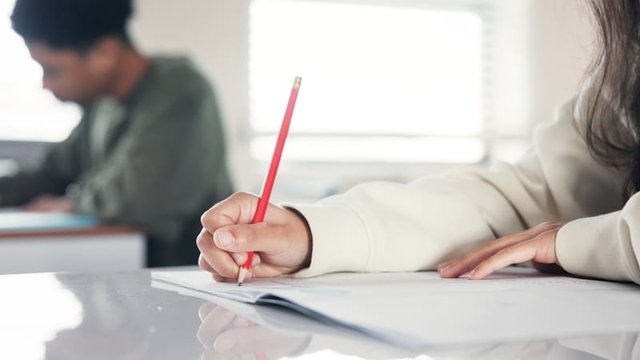 mano adolescente escribe con lápiz en un cuaderno