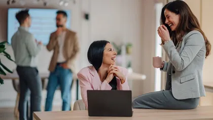dos empresarias comparten una conversación animada durante una reunión informal en una oficina moderna