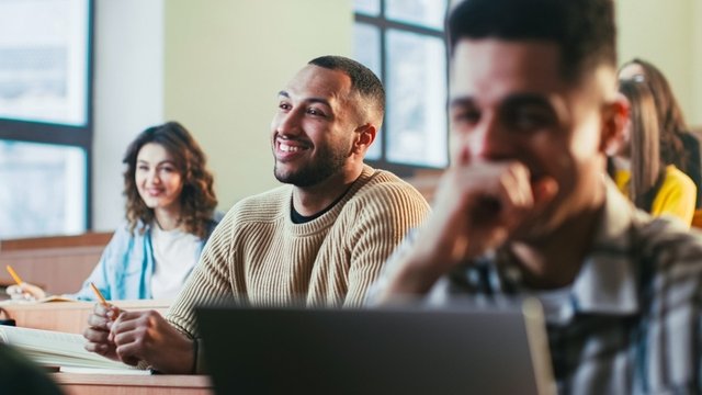 estudiantes de oposiciones atendiendo en clase y sonriendo