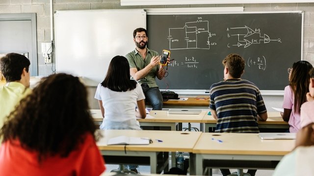 profesor impartiendo una clase de tecnología a estudiantes de secundaria