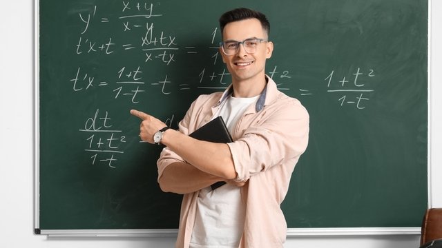 profesor de matemáticas señalando lo que hay escrito en una pizarra