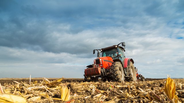 agricultor arando el campo con un tractor rojo