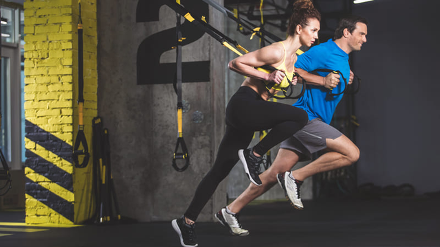 Vista lateral de dos personas concentradas haciendo ejercicio en un gimnasio