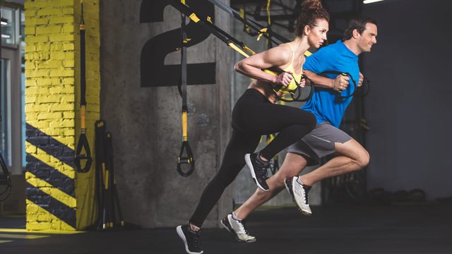 Vista lateral de dos personas concentradas haciendo ejercicio en un gimnasio