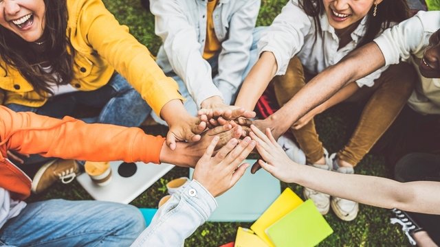 jóvenes que juntan sus manos como símbolo de unidad y trabajo en equipo