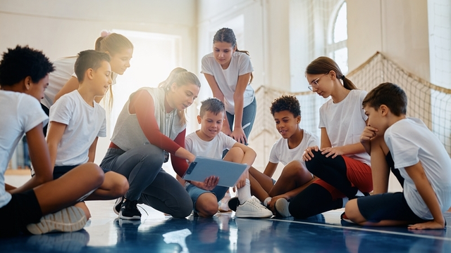 profesora de Educación Física con sus estudiantes analizando el plan de juego