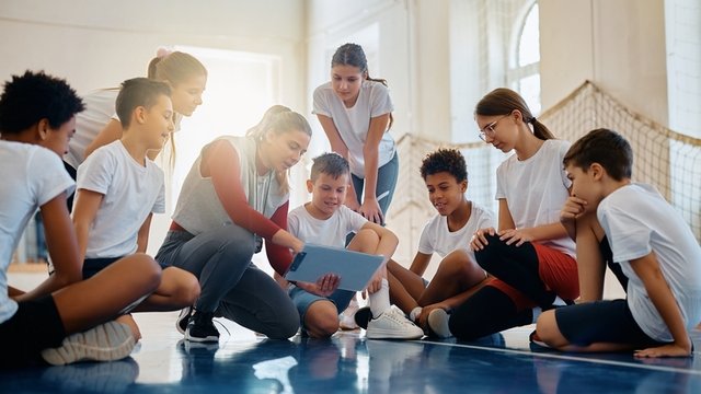 profesora de Educación Física con sus estudiantes analizando el plan de juego