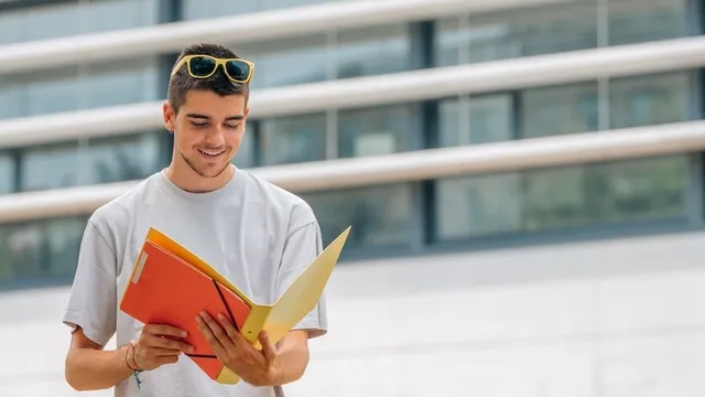 estudiante leyendo unos documentos que se encuentran dentro de una carpeta que sostiene entre manos