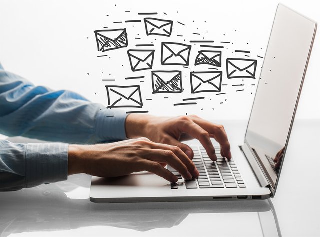 Profesional trabajando en laptop con ilustraciones de correos electrónicos saliendo de la pantalla, representando estrategia de email marketing