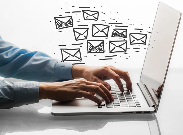 Profesional trabajando en laptop con ilustraciones de correos electrónicos saliendo de la pantalla, representando estrategia de email marketing