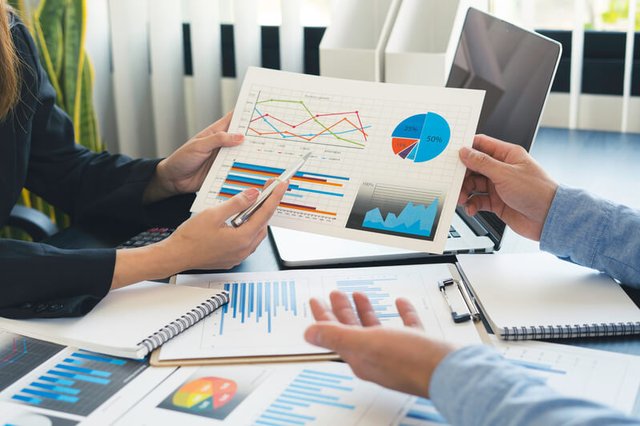 Personas conversando sobre ingresos, egresos y gastos sobre papeles con gráficos