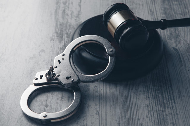 El mazo de un juez y un par esposas sobre la mesa simbolizando la justicia penal