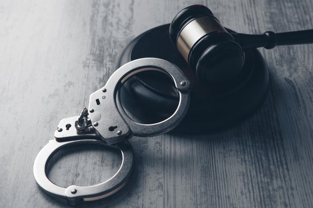 El mazo de un juez y un par esposas sobre la mesa simbolizando la justicia penal