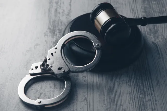 El mazo de un juez y un par esposas sobre la mesa simbolizando la justicia penal