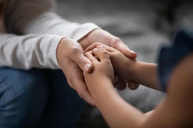 Manos de una madre rodeando las manos pequeñas de un niño en señal de protección