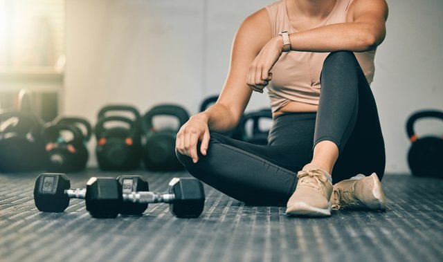 mujer sentada entrenando con pesas
