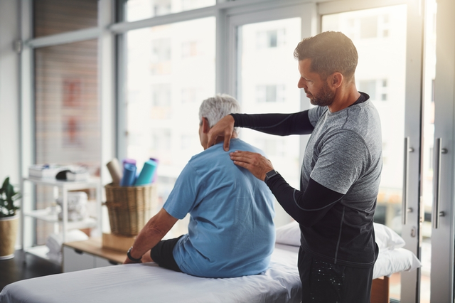 Fisioterapeuta aplicando t&eacute;cnicas de masoterapia a un hombre
