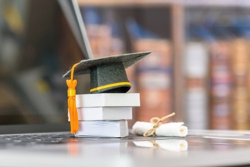 Rolled-up diploma with red ribbon on a laptop