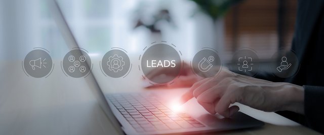 Profesional trabajando en ordenador con iconos relacionados a la captación de leads: altavoz, usuarios, imán, herramientas, nurturing y en medio el texto LEADS