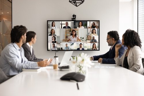 Business team in a meeting room having a video conference with remote colleagues on a large screen