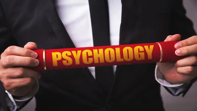 Person in a suit holding a red diploma tube with the word "Psychology" printed on it