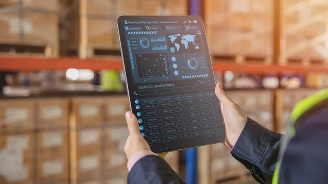 unas manos sostienen una tableta donde se puede ver la interfaz de un software logístico
