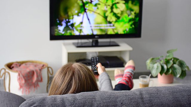 persona sentada en el sofá de su salón ve una película subtitulada