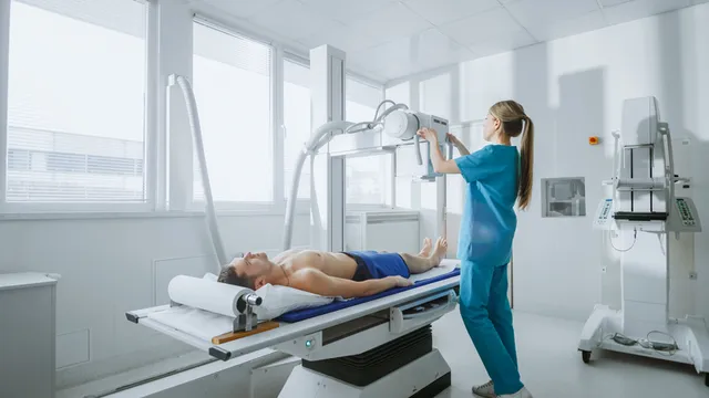 chica técnico de rayos prepara el equipo para hacer una prueba a un paciente