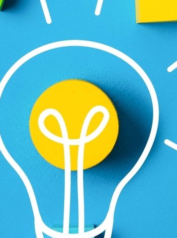 formas geométricas de colores alrededor de una bombilla y sobre un fondo azul