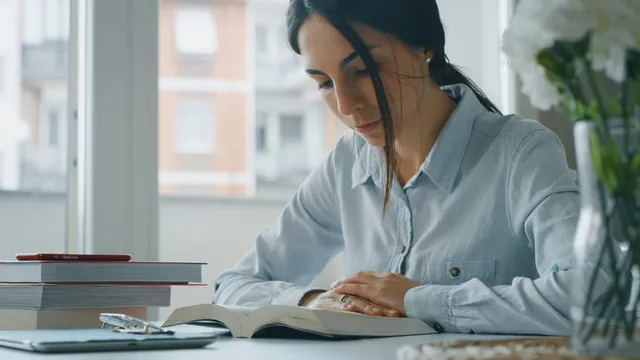 Chica joven leyendo un libro, preparándose para un examen