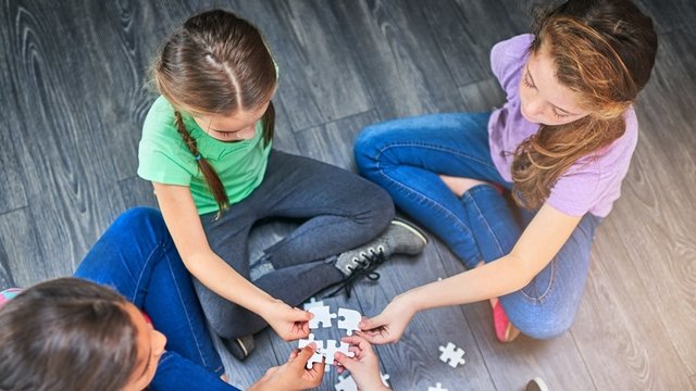 niños sentados en círculo uniendo en medio las piezas de un puzle