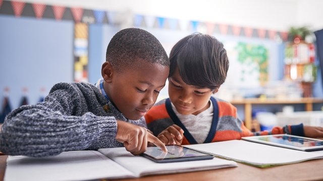 dos compañeros de clase trabajando juntos en un proyecto con una tablet