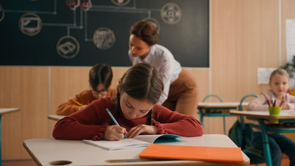 clase de un colegio en la que una profesora ayuda a sus alumnos mientras estudian