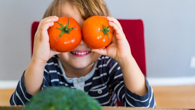 imagen de un niño con dos tomates y un brocoli